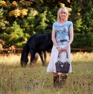 Sue Roake Standing in a Field Holding a Leather Purse with Horse in Background